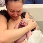 Kaleigh holding newborn baby, born with Amy as doula support